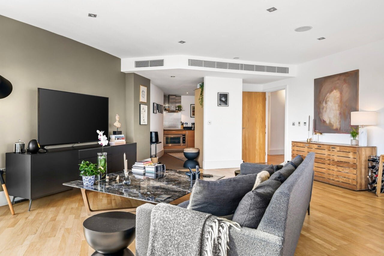 Modern living room with grey sofas, wooden flooring, and contemporary decor.