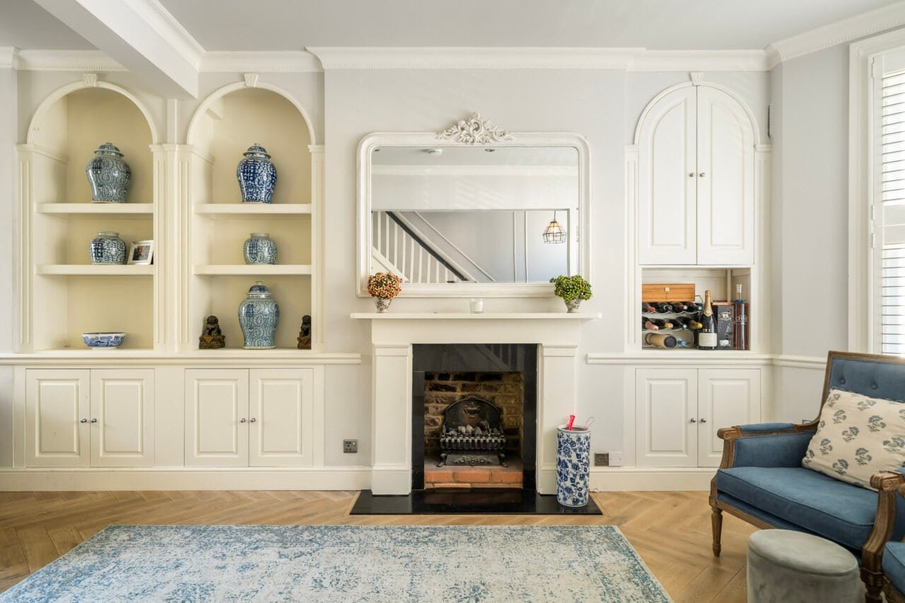 A cosy living room with white built-in shelves, fireplace, and blue accents.