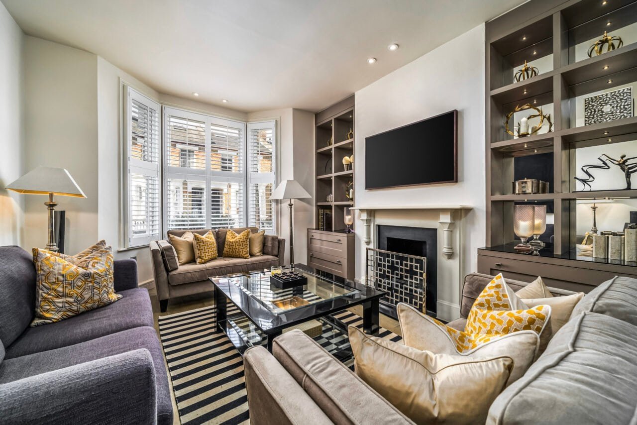 A cosy living room with modern furniture, fireplace, and large bay window.