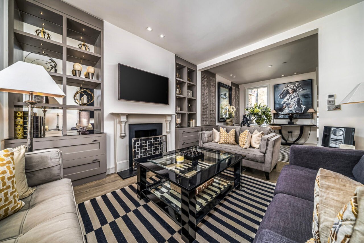 Modern living room with grey sofas, fireplace, and entertainment area, stylish interior design.