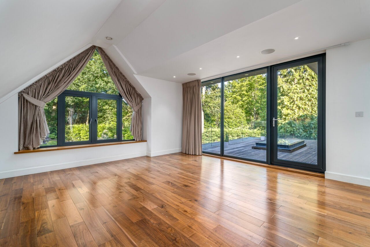 Spacious modern living room with large windows and wooden flooring, bright and airy.