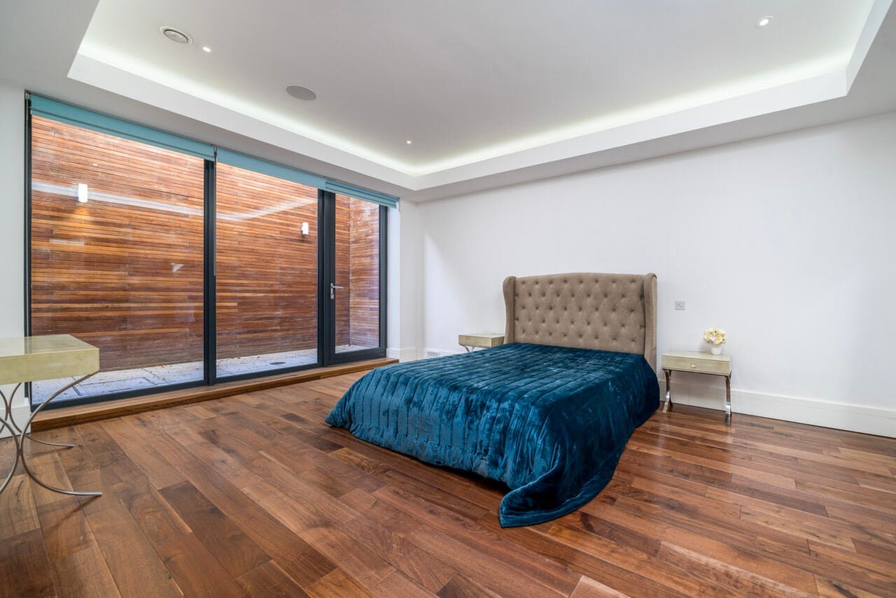 Modern bedroom with large glass sliding doors and wooden flooring.