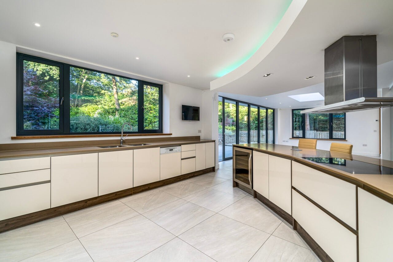 Modern kitchen with large windows, white cabinets, and sleek design.