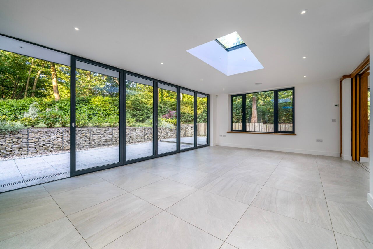 A modern, spacious living room with large glass sliding doors and a skylight.