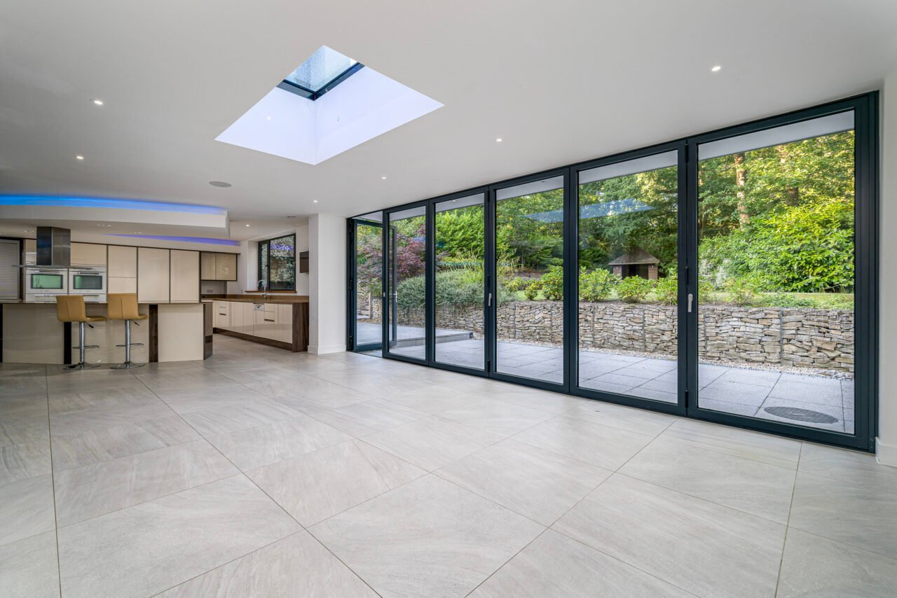A spacious modern living area with large glass sliding doors and a skylight.