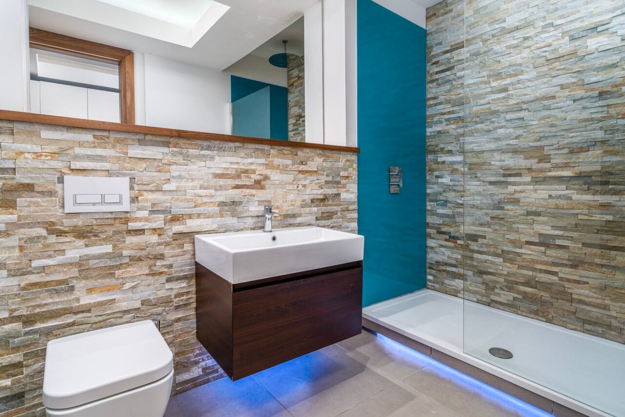 Modern bathroom with stone wall tiles, walk-in shower, and contemporary fixtures.