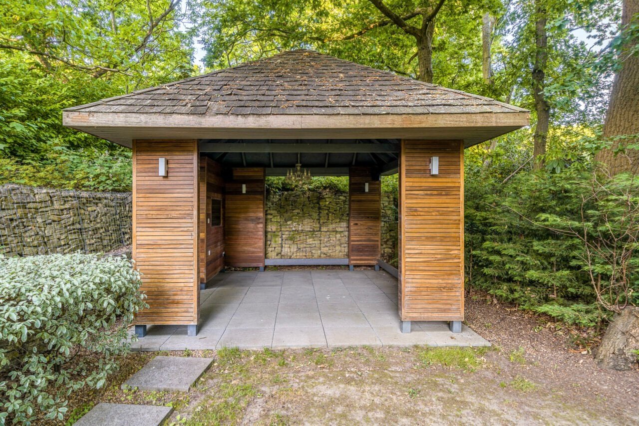 A lush green garden with a wooden gazebo and stone pathway in a peaceful outdoor setting.