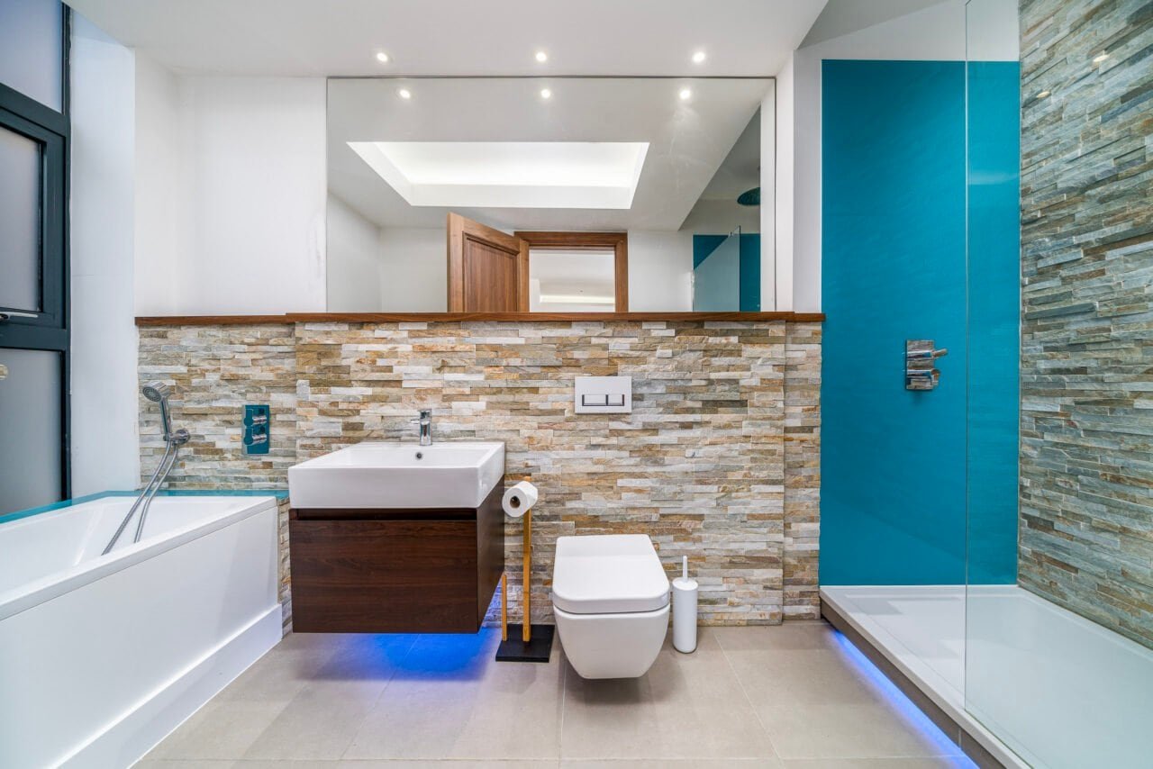 A bathroom with a bathtub, modern sink, toilet, and glass shower enclosure, stylish interior design.