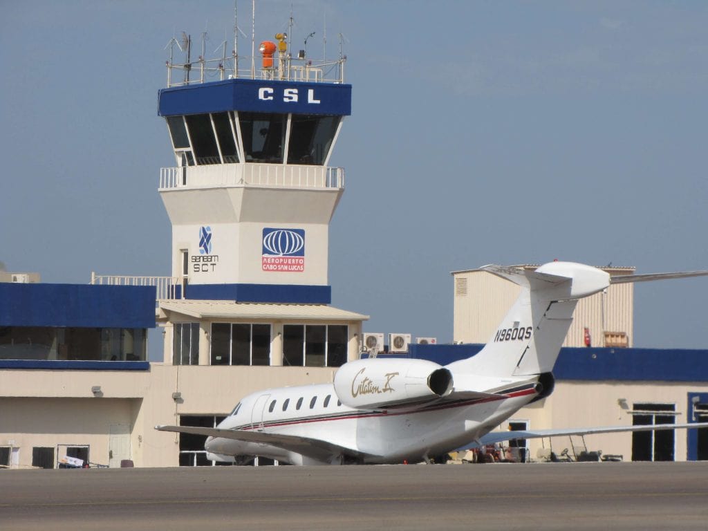 Private Jet Parked At Puerto Los Cabos Airport With Air Traffic Control Tower In The Background, Showcasing Luxury Transportation Options In Puerto Los Cabos.
