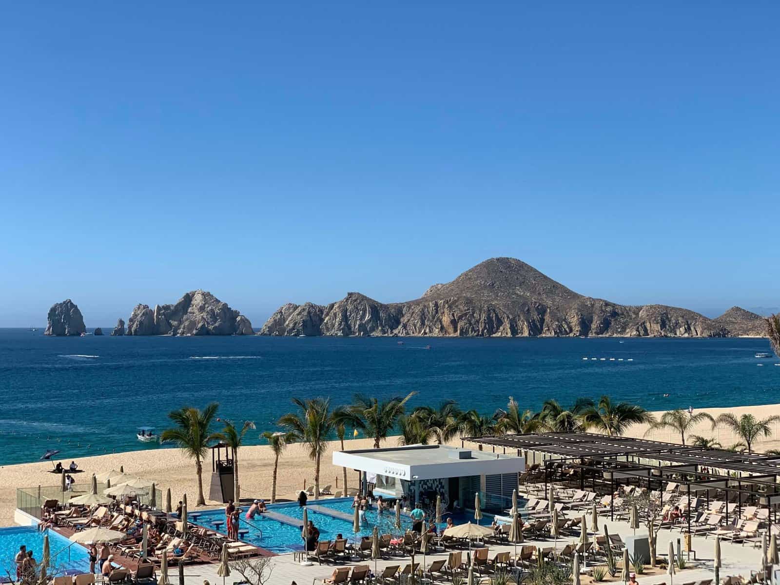 Is Cabo San Lucas Safe In 2025? What Puerto Los Cabos Visitors And Homeowners Should Know – Homes For Sale In Plc Gorgeous View Of Islands Of Loreto From Puerto Los Cabos Beach, Featuring A Pool Area With Lounge Chairs, Palm Trees, And Clear Blue Waters, Perfect For Relaxing In Puerto Los Cabos. Answering The Question , Is Cabo San Lucas Safe?
