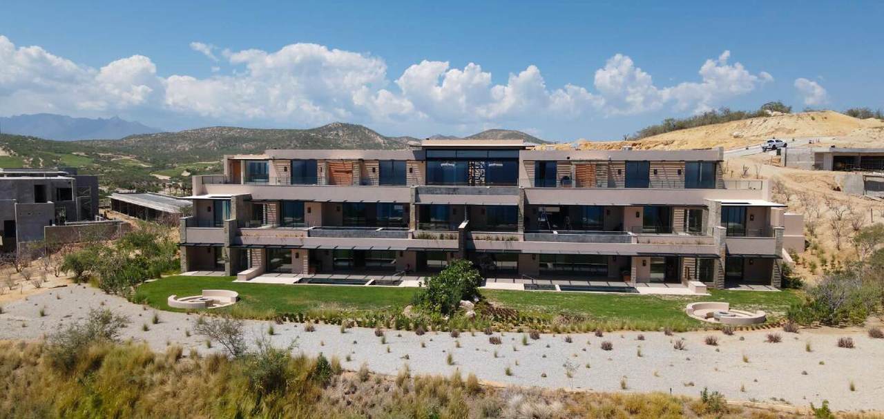 Luxury Modern Residential Building In Puerto Los Cabos With Scenic Desert And Mountain Views, Landscaped Gardens, And Contemporary Architecture.