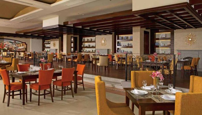 Luxury Dining Area In Puerto Los Cabos With Elegant Decor, Warm Lighting, And Beautifully Set Tables Overlooking The Resort'S Inviting Ambiance.