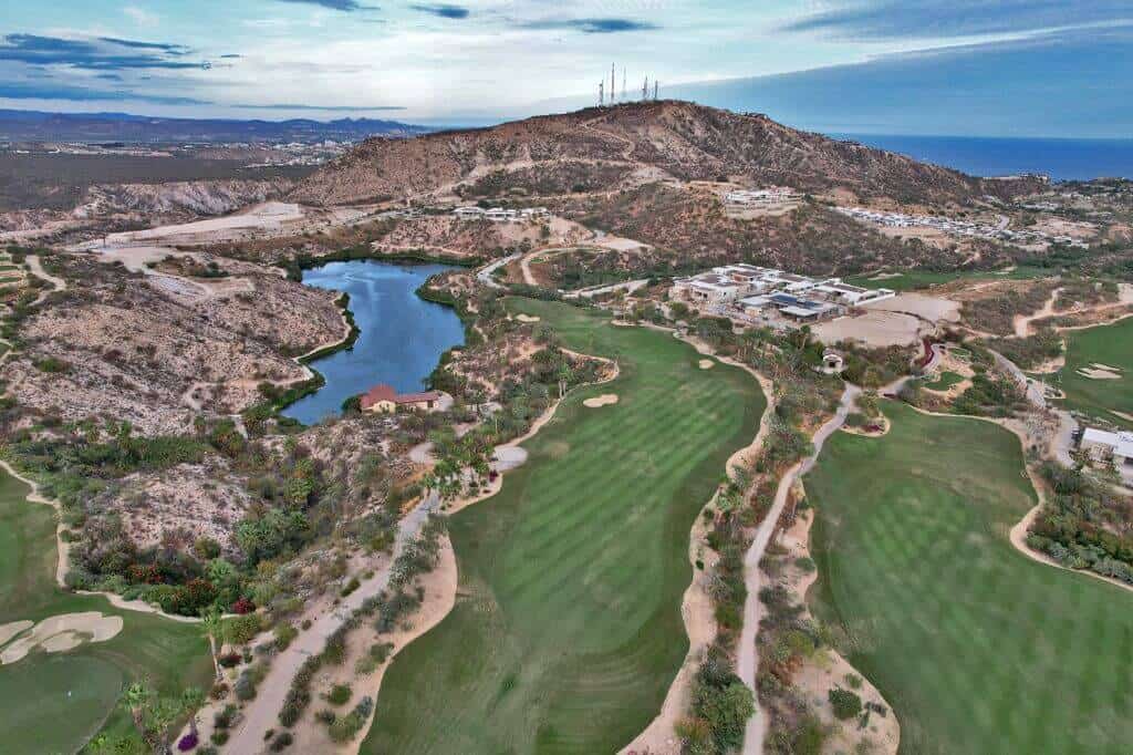 Querencia Golf Club Hole With Desert Landscape, Lush Greens, And Mountain Backdrop
