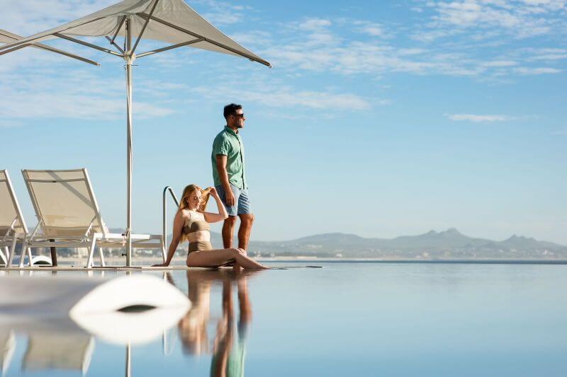 Relaxing by the infinity pool at Querencia Real Estate with a scenic view of mountains and clear blue sky.
