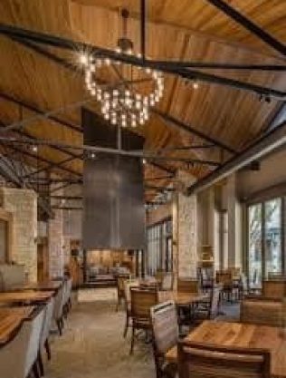 Elegant Interior Of Querencia Real Estate Showroom, Featuring A Modern Chandelier, Wooden Accents, And Spacious Dining Area For A Luxurious Real Estate Experience.