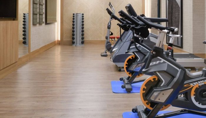 Indoor Gym With Modern Exercise Bikes And Free Weights At Querencia Real Estate Fitness Center.