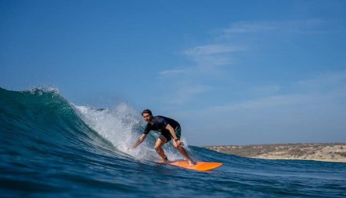 Surfing In Ocean Waves At Sunset For Querencia Real Estate.