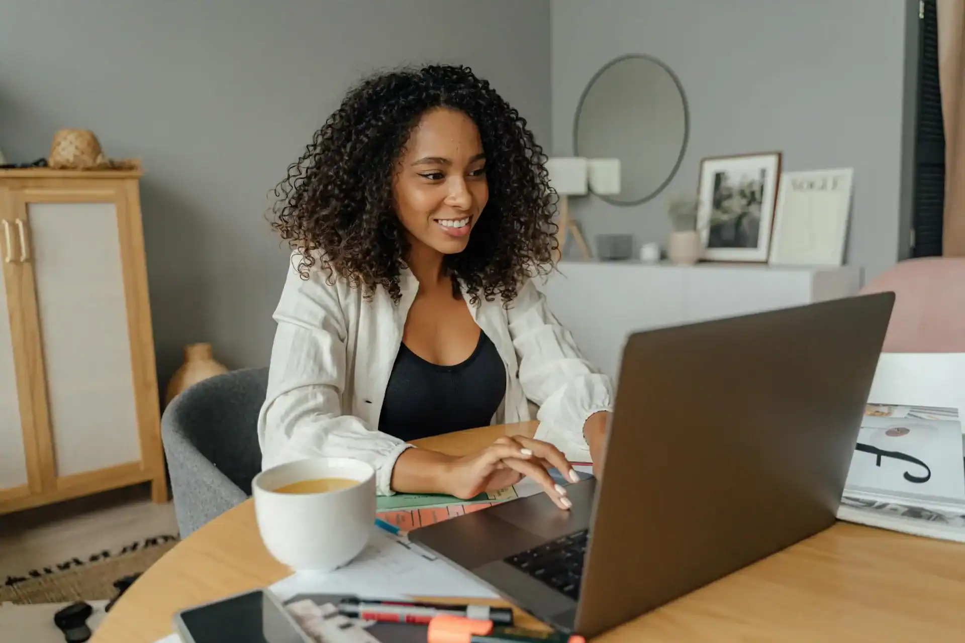 Imagem de uma mulher usando um laptop em cima de uma mesa.