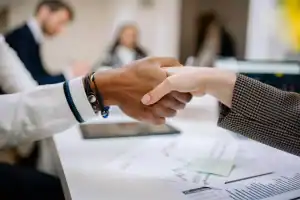 Imagem de duas pessoas apertando as mãos.