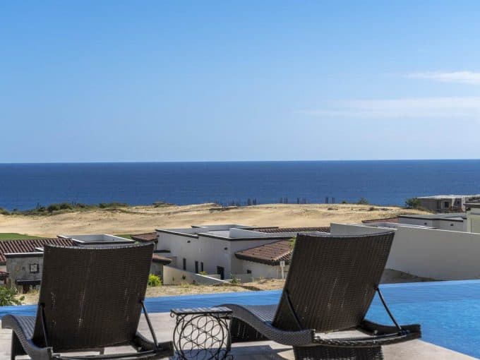 Panoramic View Of The Ocean From A Luxurious Balcony At Quivira Los Cabos, Showcasing Pristine Blue Waters And Modern Homes Beneath A Clear Sky.