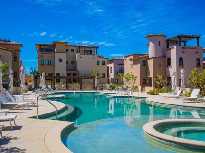 Luxurious Swimming Pool At Quivira Los Cabos Real Estate Community, With Modern Villa-Style Buildings And Lush Landscaping, Offering A Perfect Retreat In A Scenic Baja California Sur Setting.