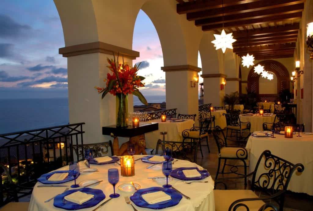Elegant Outdoor Dining Area At Quivira Los Cabos With Stunning Ocean Views, Moroccan-Style Star-Shaped Lanterns, And Candlelit Tables, Perfect For A Luxurious Dining Experience.
