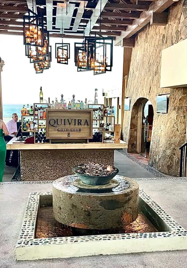 Quivira Los Cabos Resort Bar Area With Elegant Lighting And Ocean View, Luxurious Interior Of Quivira Los Cabos Real Estate, Stylish Bar Setup At Quivira Los Cabos Golf Club With Decorative Fountain, Inviting And Sophisticated Ambiance In Quivira Los Cabos Property, Relevant For Luxurious Quivira Los Cabos Real Estate Marketing.
