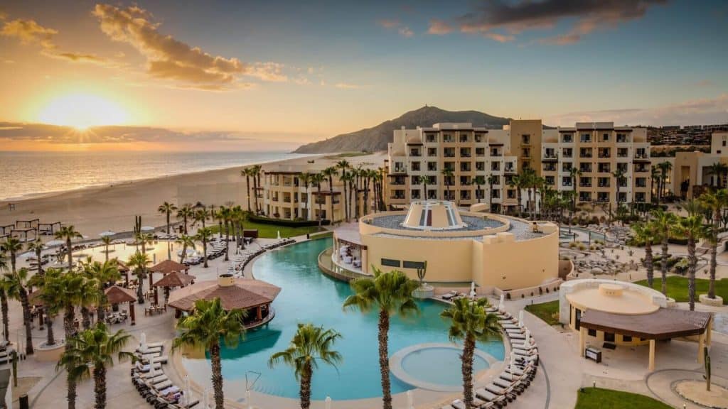 Luxurious Quivira Los Cabos Resort With Infinity Pool, Beachfront Access, And Stunning Mountain Views During Sunset.