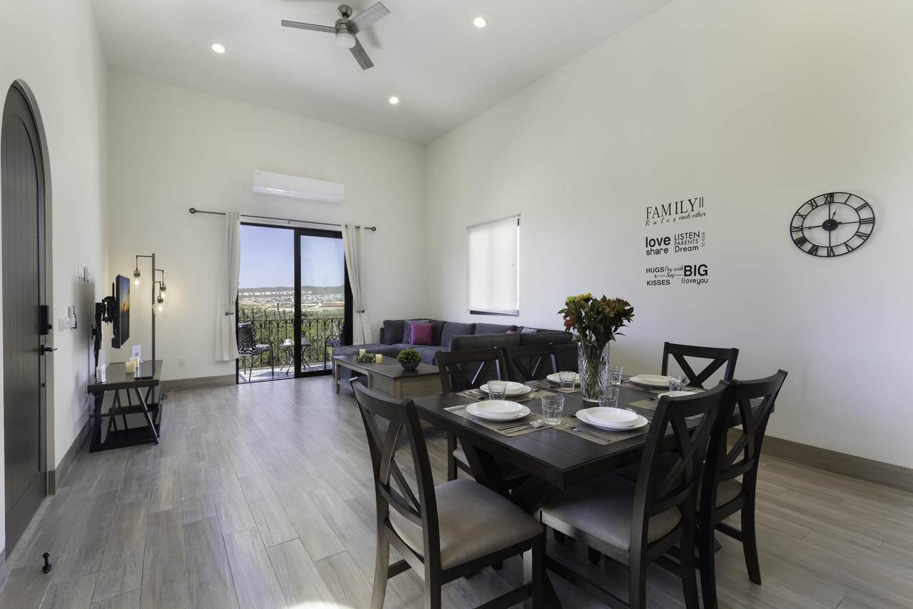 Spacious Living And Dining Area At Quivira Los Cabos Real Estate, Featuring Modern Decor, A Balcony With Scenic Views, And Open-Plan Design Ideal For Family Living And Entertaining.