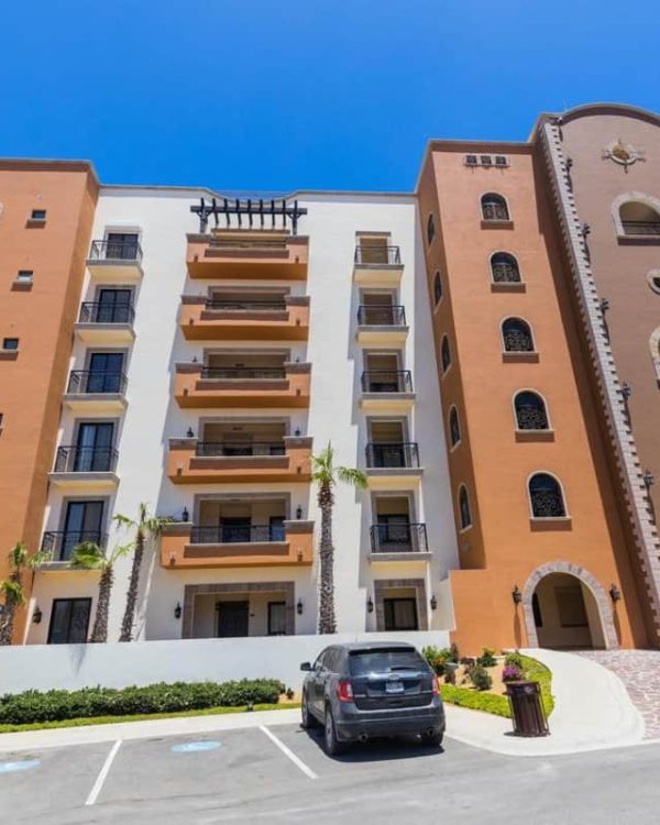 Exterior view of Tower 5 Copala at Quivira, showing the Mediterranean-style architecture, balconies, and parking area in Cabo San Lucas, Baja California Sur