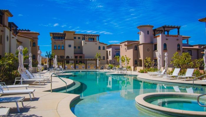 Quivira Resort Communal Pool Area Surrounded By Spanish Colonial Style Residential Buildings And Lounge Chairs.
