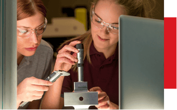 Microscope with two women conducting scientific research in a laboratory setting, emphasizing quality control and precision testing in automation processes.