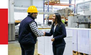 High-tech industrial automation experts shaking hands in a manufacturing facility, showcasing innovative solutions for streamlining production processes and improving operational efficiency.