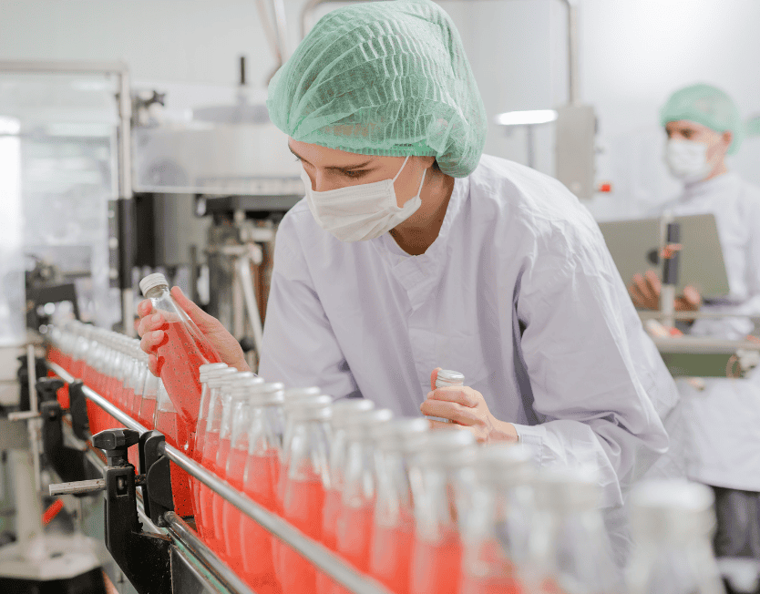 Bottled beverage production in a clean pharmaceutical-grade facility, with workers inspecting bottles for quality control, emphasizing automation and precision in beverage filling processes.