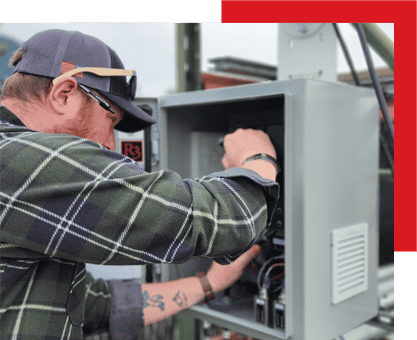 Advanced industrial automation technician working on electrical control panels in a manufacturing facility.