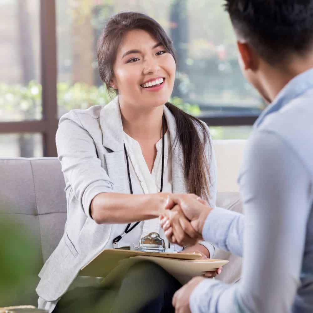 Wellbeing coach shaking hands with client in a professional setting