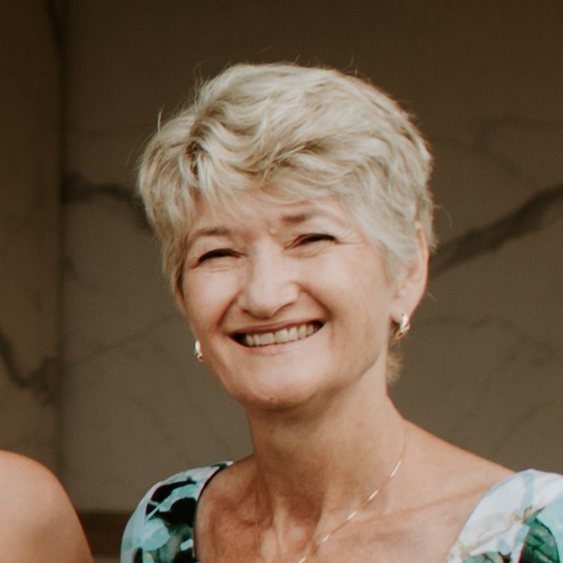 Senior woman smiling warmly outdoors, showcasing happiness and vitality.