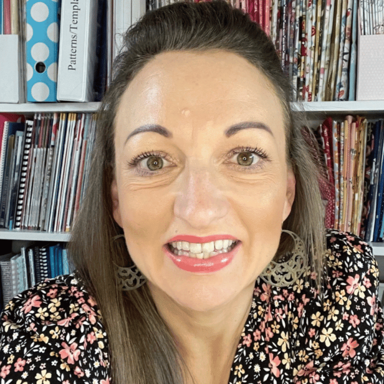 Woman smiling in a library with colorful books in the background.