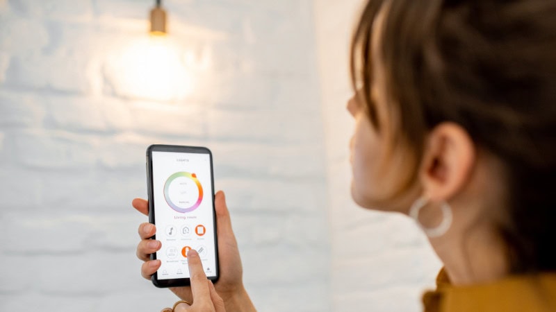 A woman is adjusting the lights by smart lighting control system