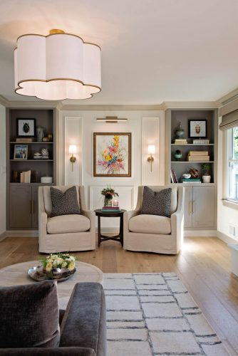 Bright living room with real wood flooring, cozy armchairs, and built-in shelves.