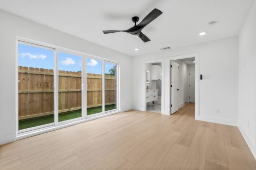 Sleek bedroom with wide windows and wide plank wood composite flooring