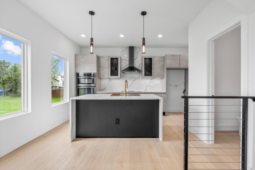 Kitchen with built-in appliances, textured cabinetry, and wide plank composite flooring