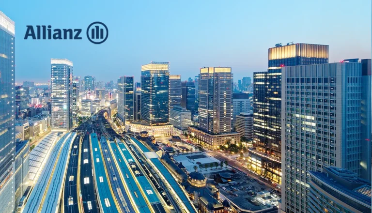 Aerial view of a modern city skyline at dusk with winding train tracks in the foreground and an Allianz logo in the upper left.
