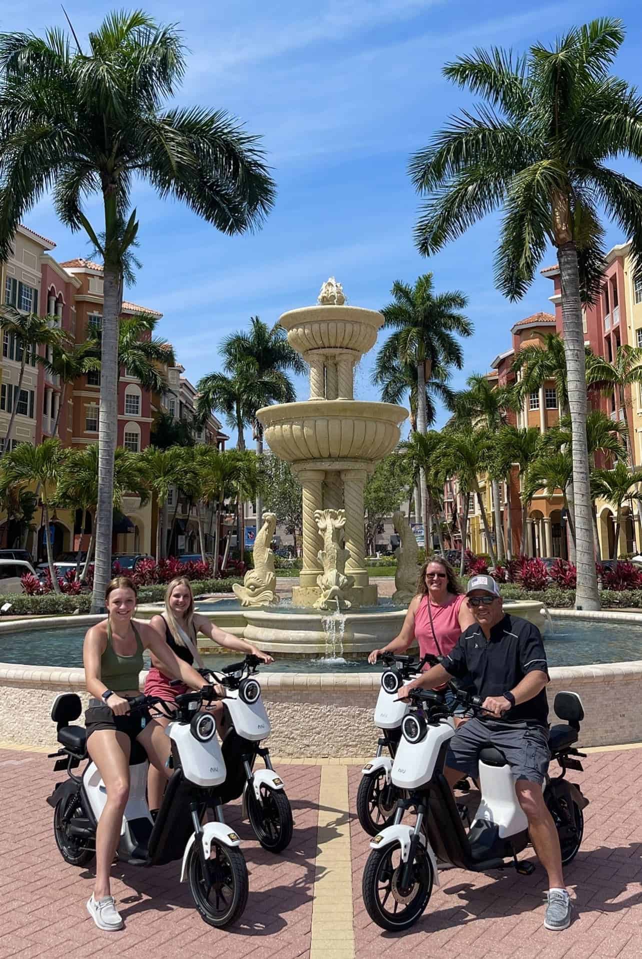 Moped riders passing Tin City Waterfront Shops Naples