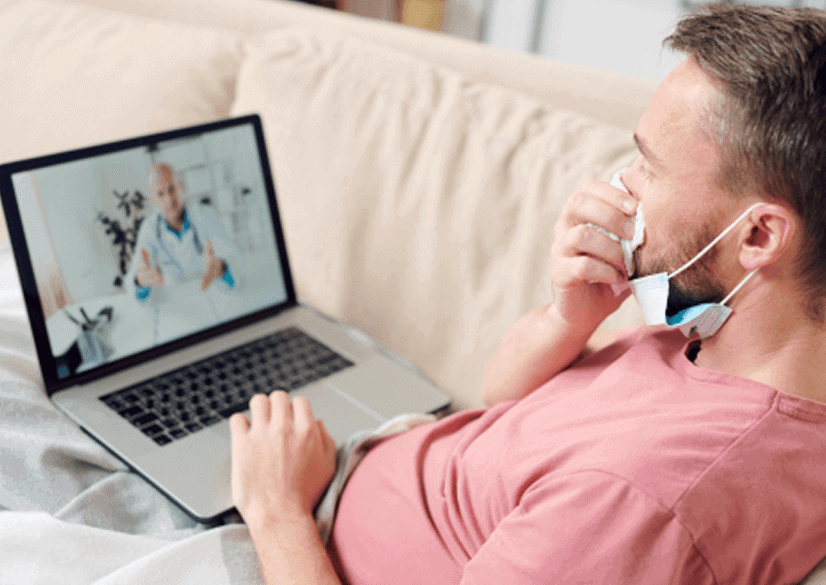 young sick man with laptop blowing his nose while sitting couch blanket having rest listening recommendations online doctor 1 1