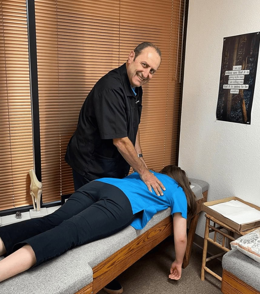 Chiropractor performing spinal adjustment on patient in clinic.