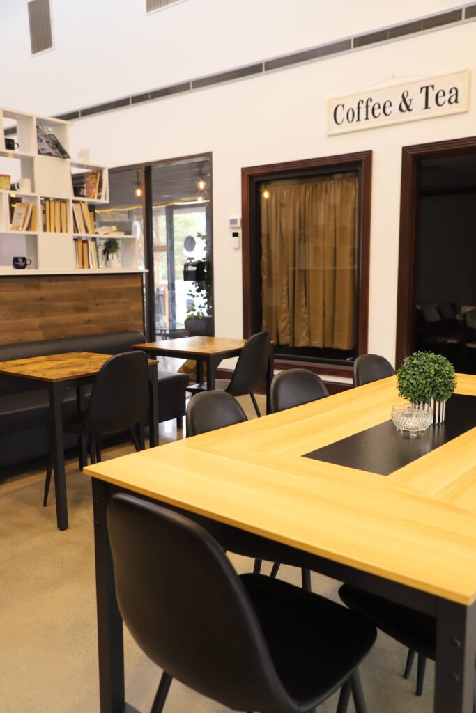 Next Steps Training Program & Riverside Coffee 6 Modern coffee shop interior with wooden tables and black chairs.