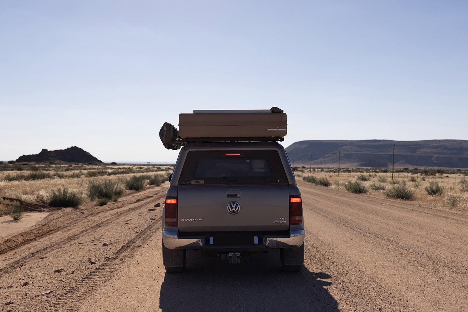 Stainless steel canopy installed on a Volkswagen Amarok pickup truck in a desert landscape, showcasing durable and sleek RLD Design stainless steel canopies for utility vehicles.