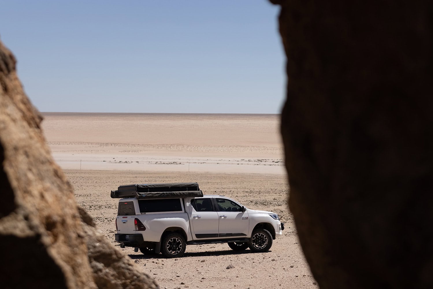 RLD Design stainless steel canopy on a white pickup truck in a desert landscape with a view framed by rocks.