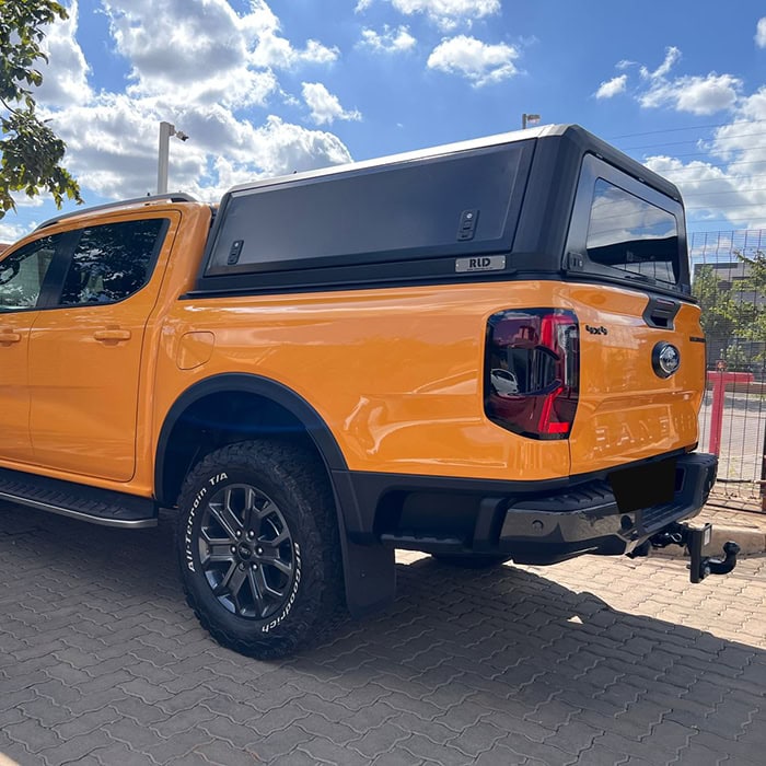 High-quality stainless steel canopy installed on a bright orange pickup truck for enhanced outdoor protection and stylish vehicle customization.